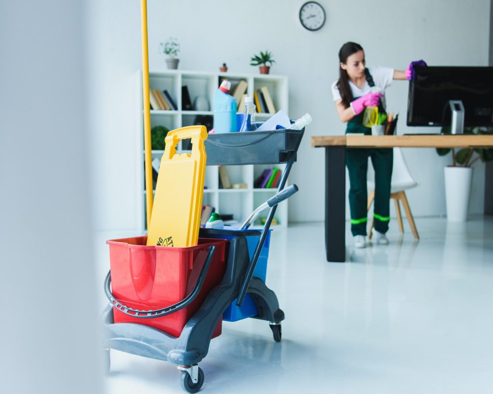 Female janitor cleaning office desk